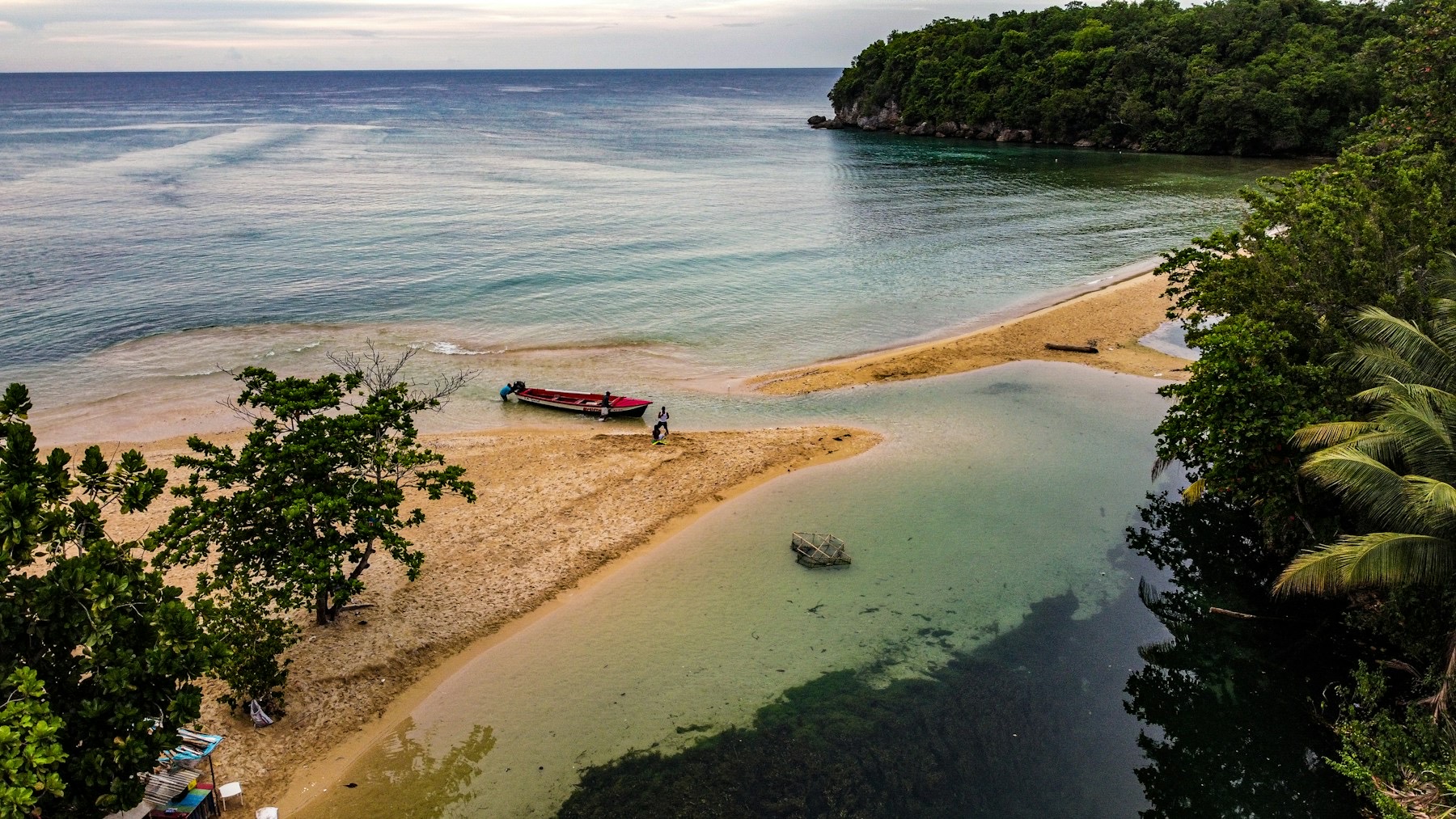A sandbar and a fishing boat on the shore near Ocho Rios, with green hills beyond