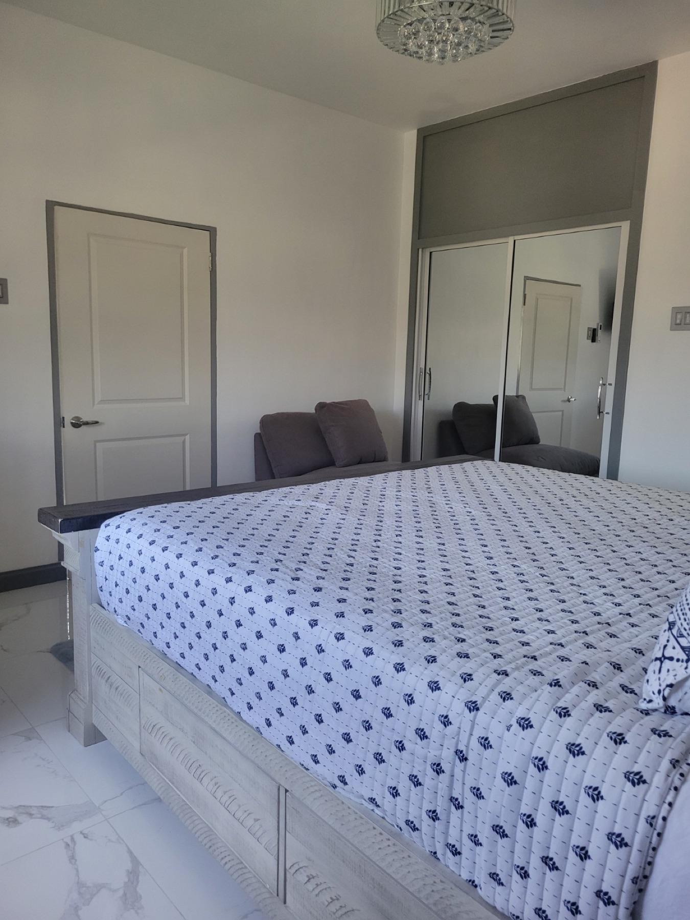 An en-suite bedroom with white and blue bedding and a marble floor