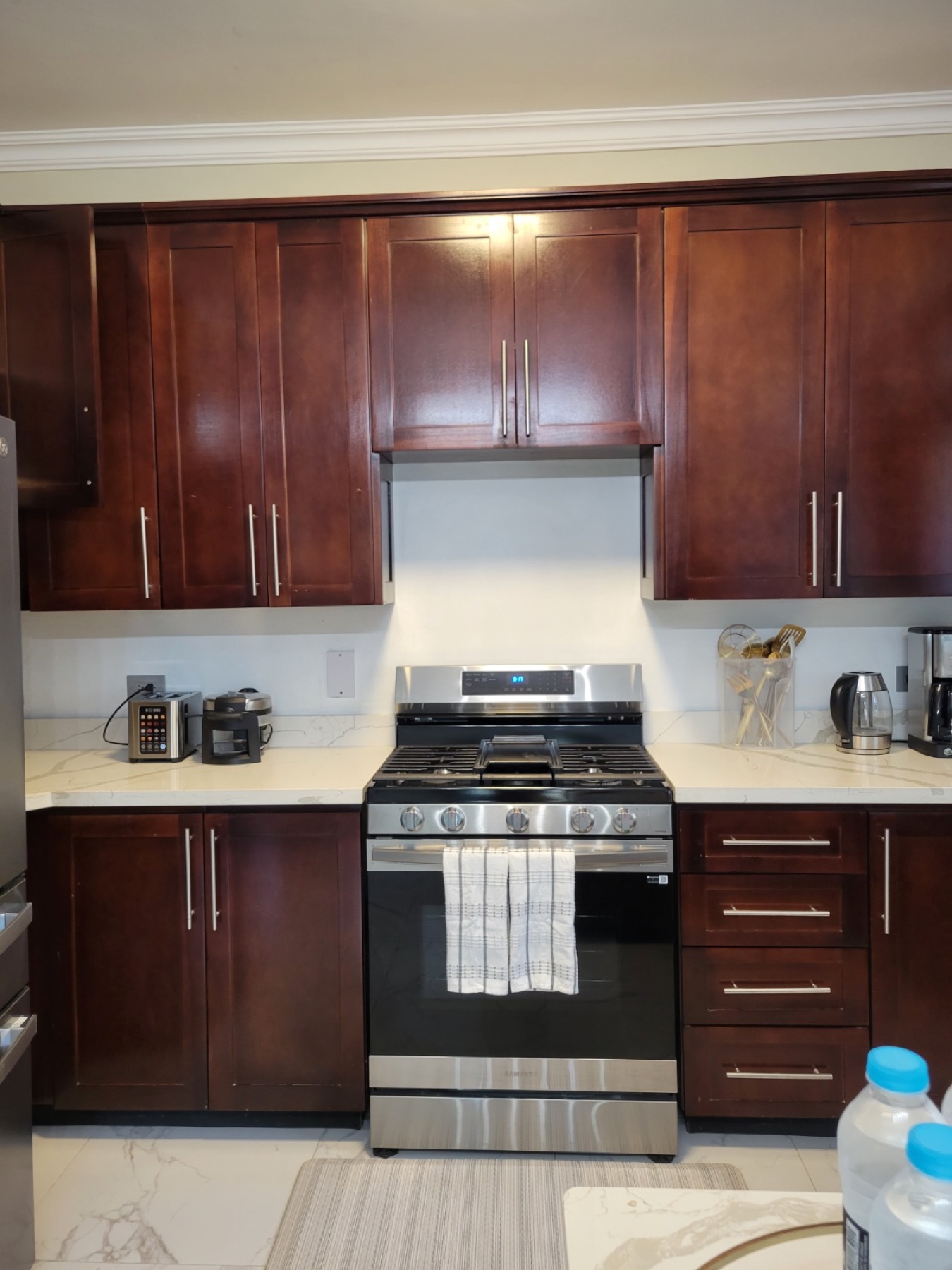 The kitchen with dark wood cabinets, a gas range and a full set of appliances