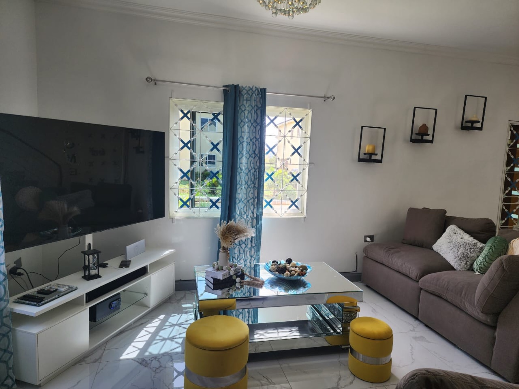 Jade's open living area with a sofa, a large smart TV and a window to the garden