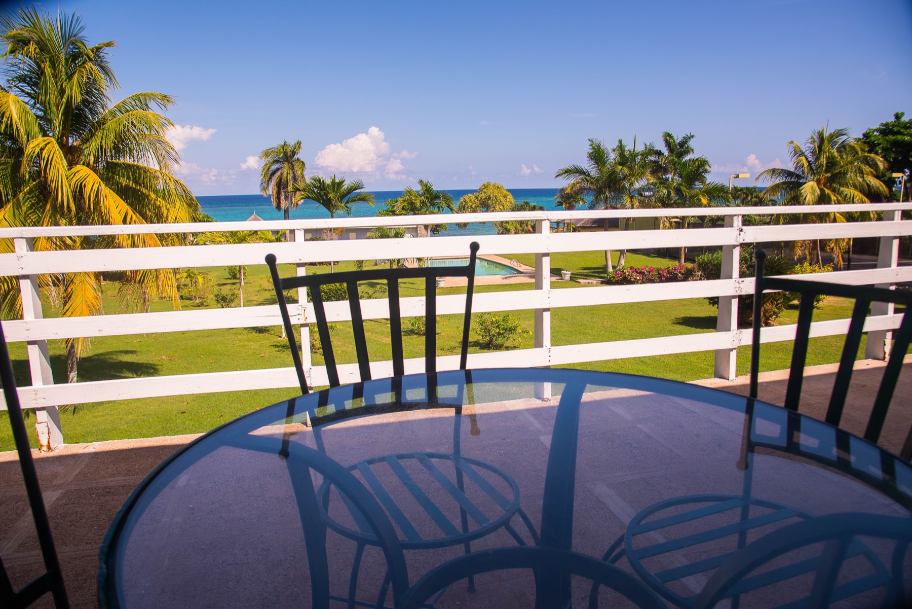 The view from the balcony at Miramar Villas: table and chairs, palms and the sea beyond