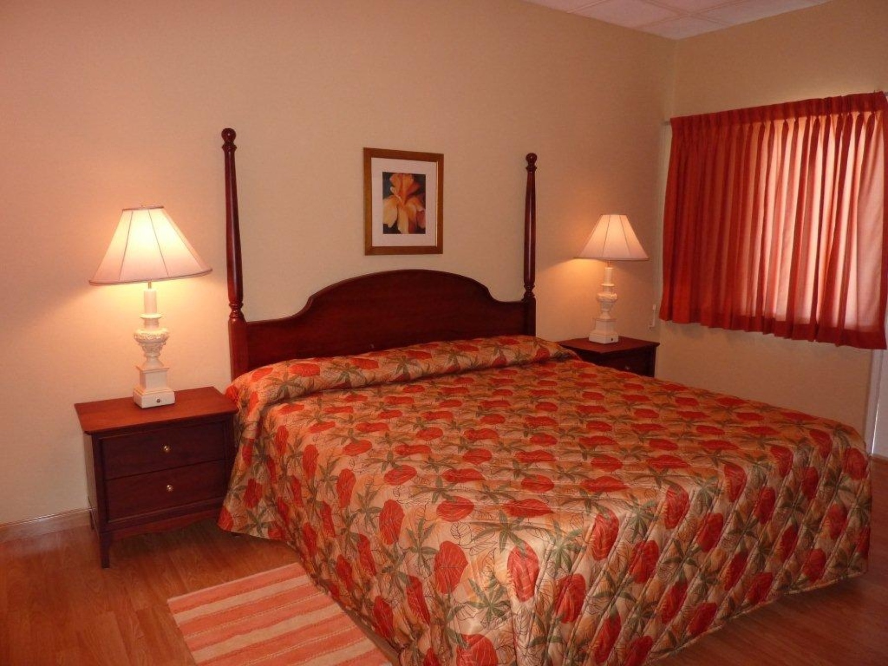A king bedroom with a four-poster bed, bedside lamps and a tropical spread
