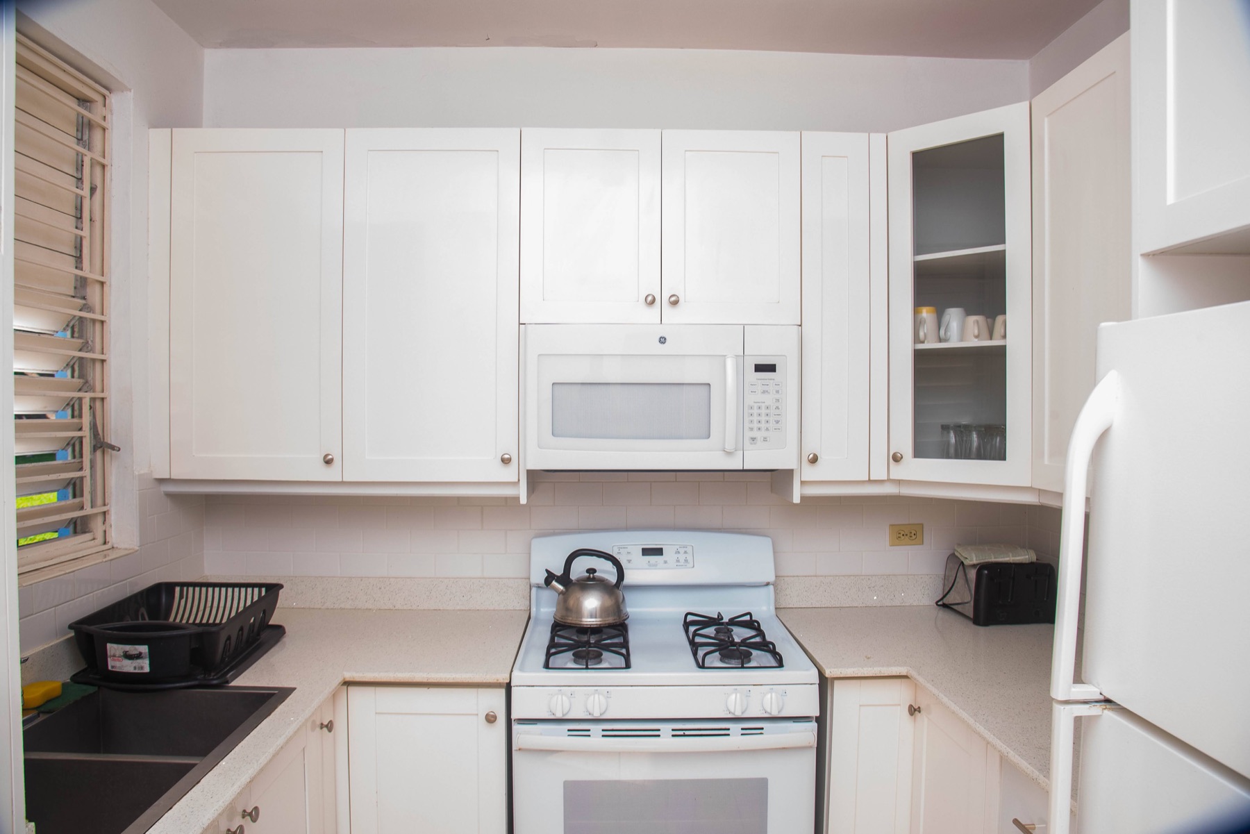 The full kitchen with white cabinets, a gas range and a microwave