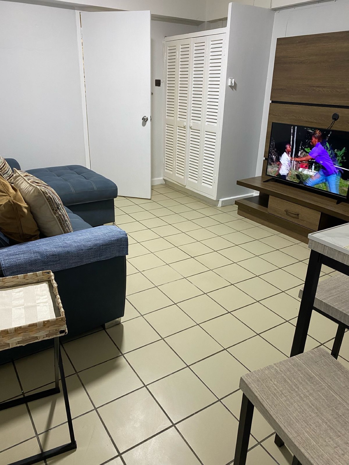 A suite's living and dining area with a sofa, smart TV and tiled floor
