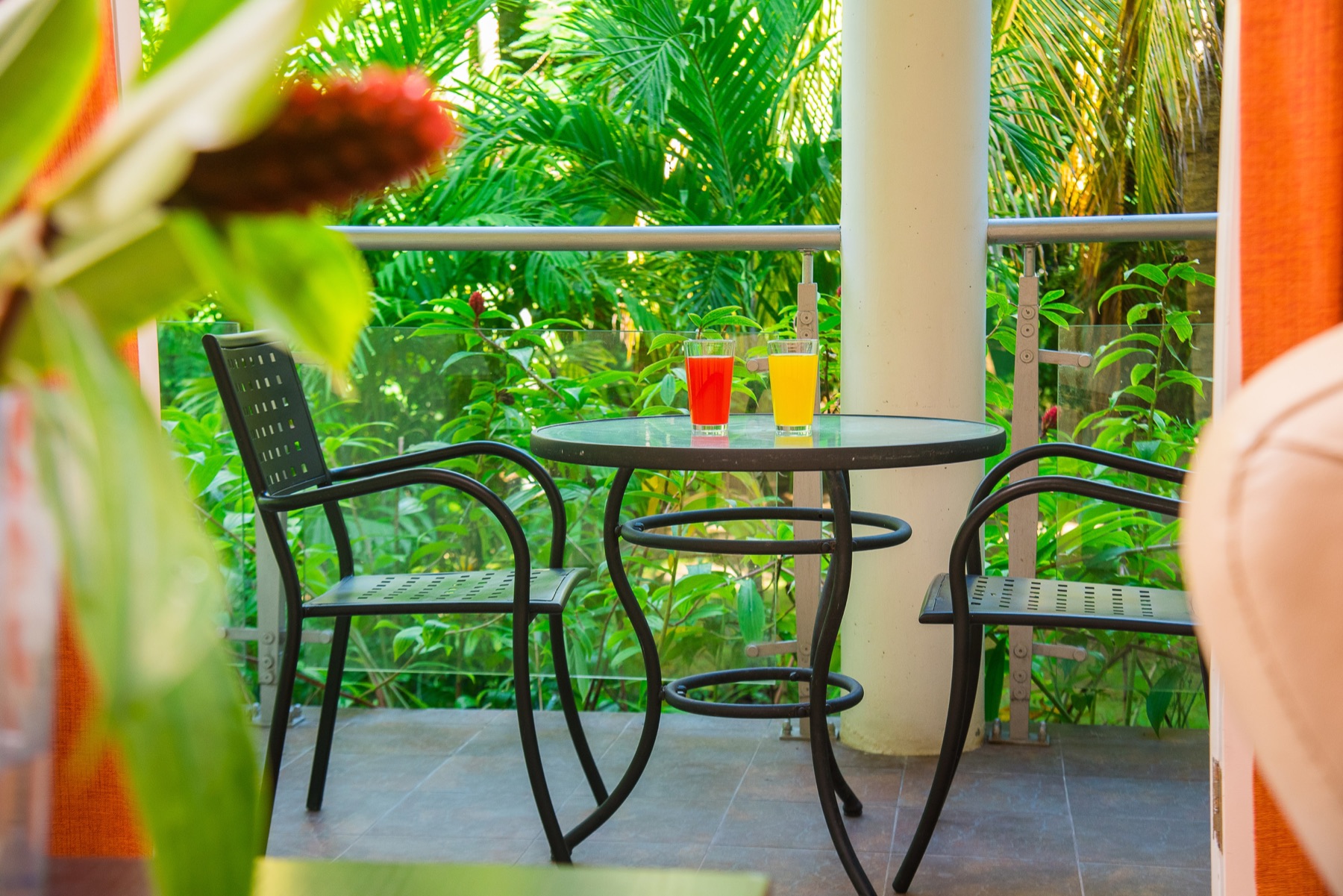 A table and chairs on the balcony at Tranquility Cove, surrounded by tropical planting