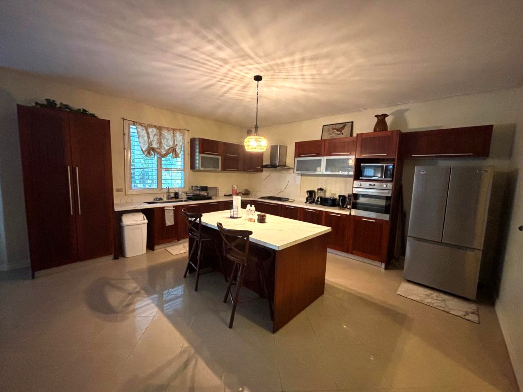 The kitchen with an island, wooden cabinets and stools to sit at