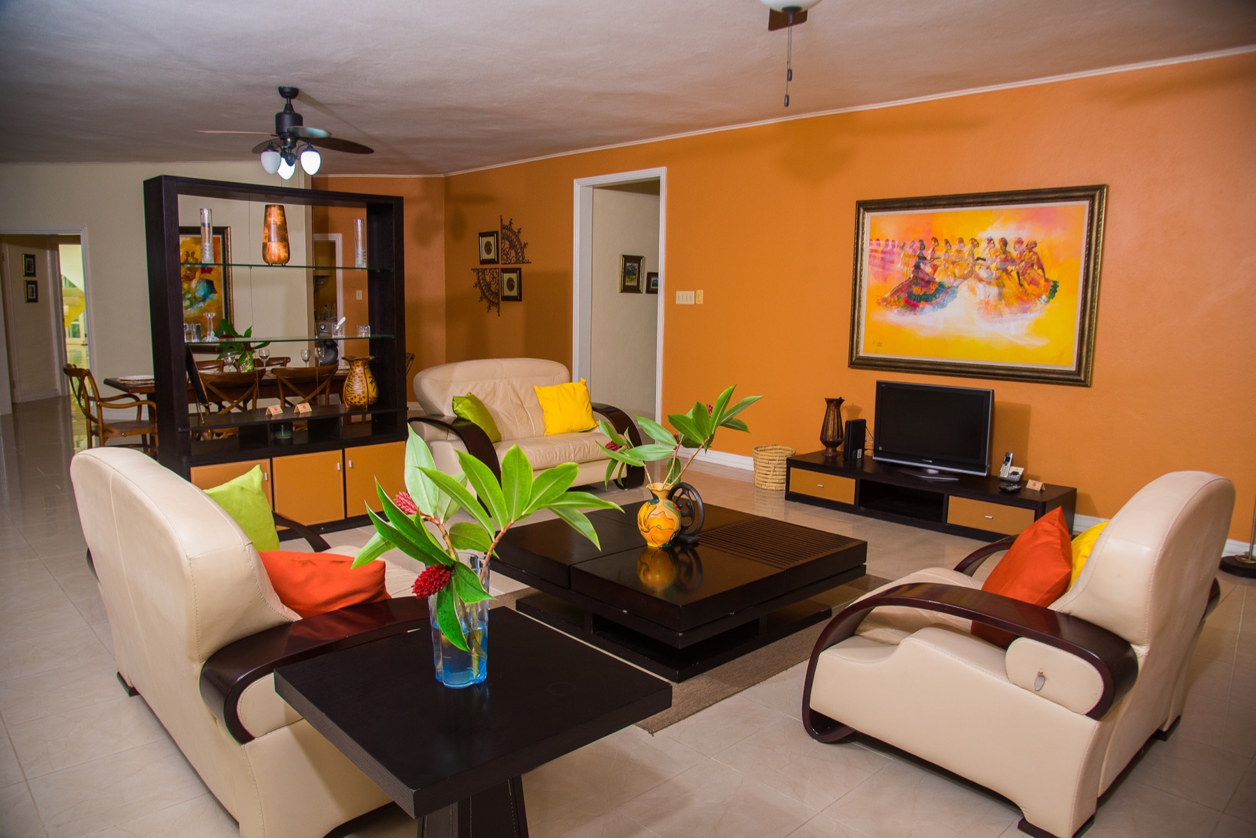 Tranquility Cove's living room: warm orange walls, cream armchairs and a low table with fresh flowers